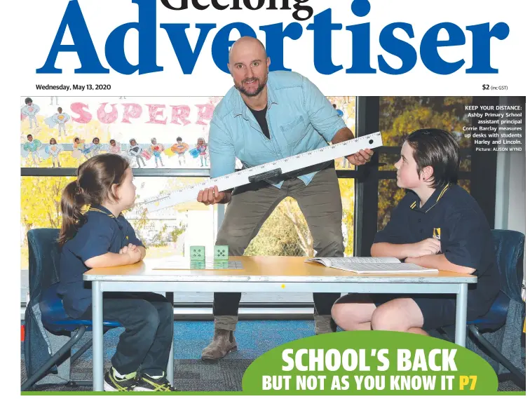  ?? Picture: ALISON WYND ?? KEEP YOUR DISTANCE: Ashby Primary School assistant principal Corrie Barclay measures up desks with students Harley and Lincoln.