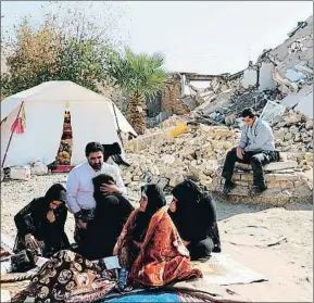  ?? ATTA KENARE / AFP ?? Una familia iraní junto a los escombros de su casa en la aldea de Kuik