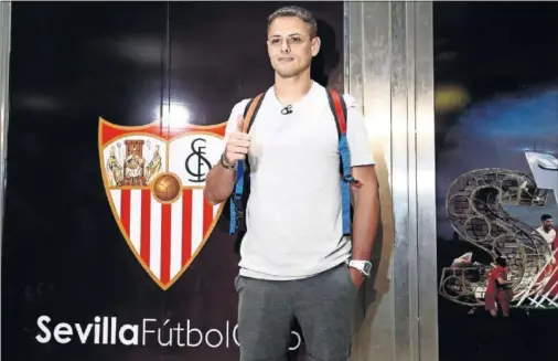  ??  ?? BIENVENIDA. Chicharito posó delante del escudo del Sevilla a su llegada al aeropuerto de San Pablo ayer por la tarde.