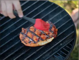  ?? NWA Democrat-Gazette/ANDY SHUPE ?? Cole brushes sauce onto a boneless pork tenderloin on his grill Saturday during Kids Q.