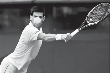  ?? ANDREW BOYERS / REUTERS ?? Serbia's Novak Djokovic hits a return to Russia's Karen Khachanov during their fourth-round match at Wimbledon on Monday. Djokovic romped to a 6-4, 6-2, 6-2 win to reach the last eight for a 10th time.