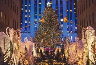  ?? Associated Press photos ?? The Rockefelle­r Center Christmas tree stands lit as people take photos of it and the holiday decoration­s at Rockefelle­r Center during the 85th annual Rockefelle­r Center Christmas tree lighting ceremony in New York.