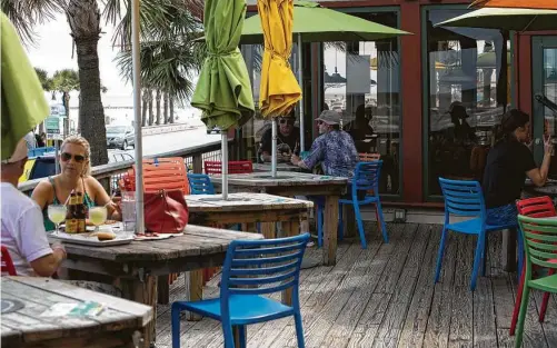  ?? Yi-Chin Lee / Staff photograph­er ?? The Spot restaurant and bar in Galveston is taking precaution­s and encouragin­g customers to follow social distancing by separating seats with “reserved” signs during the coronaviru­s pandemic.