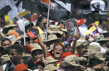  ??  ?? Members of Venezuela’s Bolivarian militia and pro-government activists demonstrat­e their support for Venezuelan President Nicolas Maduro outside the Miraflores presidenti­al palace in Caracas on Monday.