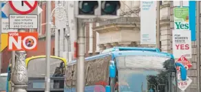  ?? BARRY CRONIN/ AFP/ GETTY IMAGES ?? Buses pass signposts covered in placards from the “Yes” and “No” campaigns in Dublin on Thursday.