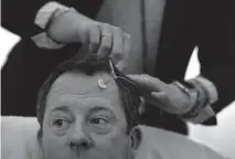  ??  ?? Whitmer puts electrodes onto the head of McCoy. The electrodes help track the brain’s electrical activity.