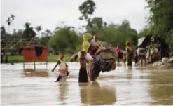  ??  ?? BALUKHALI: A Rohingya Muslim family, who crossed over recently from Myanmar into Bangladesh, walk with their belongings to find another shelter after their camp was inundated with rainwater near Balukhali refugee camp, Bangladesh yesterday.— AP