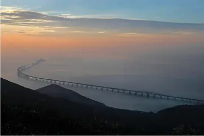  ?? AP Photo/Vincent Yu ?? ■ The Hong Kong-Zhuhai-Macau Bridge is seen Oct. 21 against the sunset in Hong Kong. The bridge, the world’s longest cross-sea project, which has a total length of 34 miles, had its opening ceremony Tuesday in Zhuhai, China.