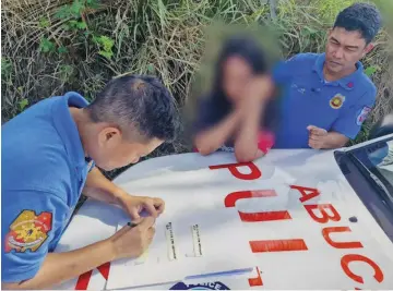  ?? PHOTOGRAPH BY MARIO SUPNAD FOR THE DAILY TRIBUNE ?? CORPORAL Roselle Supnad (left) notates the evidence which was yielded by the lady suspect (center) after her arrest along the highway of Abucay, Bataan.