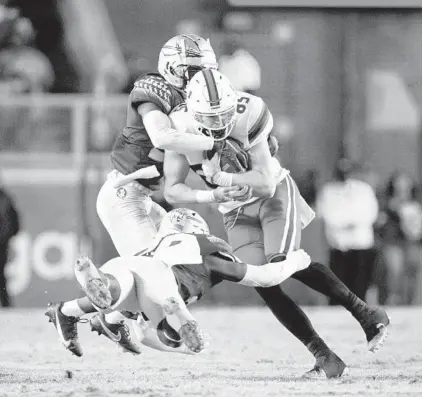  ?? MARK WALLHEISER/AP ?? Miami tight end Will Mallory (85) takes a hit from FSU linebacker Kalen DeLoach (20) and defensive back Omarion Cooper (37) in the second half of Saturday’s game.