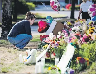  ?? AP PHOTO ?? Rachel Shuler of Burlington, Wash., takes a moment after placing a sign and balloons with her stepdaught­er at a makeshift memorial on Sunday in Burlington, to the victims the victims killed in a mall shooting on Friday.