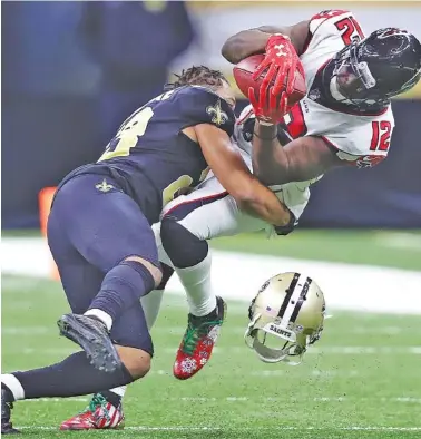  ?? THE ASSOCIATED PRESS ?? New Orleans Saints cornerback Marshon Lattimore, left, loses his helmet as he hits Atlanta Falcons wide receiver Mohamed Sanu on a reception during the third quarter Sunday in New Orleans.