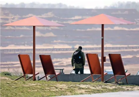  ?? FOTO: OLIVER BERG/DPA ?? Interessan­te Aussicht: Ein Mann blickt von einer Besucherpl­attform in den Tagebau Hambach. Nach dem Kohle-Aus sollen hier Seen entstehen.