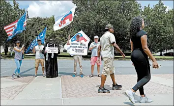  ?? CHUCK BURTON/AP ?? People walk past a group of Donald Trump and Republican National Convention supporters outside City Hall, where the Charlotte City Council voted to host the 2020 convention.