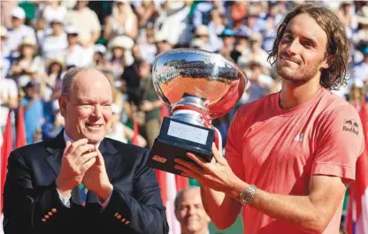  ?? (AFP) ?? Greece’s Stefanos Tsitsipas celebrates with the Monte Carlo Masters trophy next to Prince Albert II of Monaco at the Monte Carlo Country Club yesterday.
