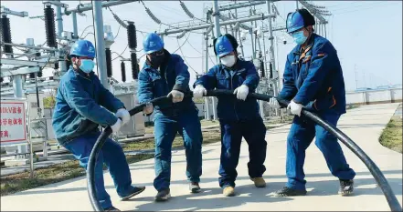  ?? SONG WEIXING / FOR CHINA DAILY ?? Employees from a power company in Chuzhou, Anhui province, install a cable at an industry park earlier this week.