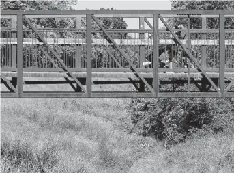  ?? Brett Coomer/Staff photograph­er ?? A family crosses a bridge that runs near Halls Bayou and Keith Weiss Park on May 12. Numerous trails, some unmarked, offer routes deep into the secluded woods.