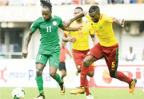  ??  ?? Nigeria and Chelsea star Victor Moses (11) moves with the ball as Cameroon players chase his shadow during the first leg of FIFA 2017 World Cup Russia in Uyo last October