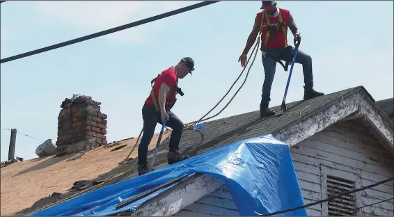  ?? (AP/Stephen Smith) ?? Actor Anthony Mackie (top right) helps to repair a roof Sept. 12 in New Orleans.