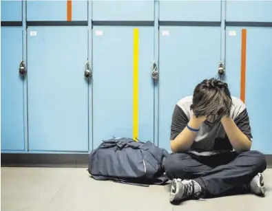  ?? EL PERIÓDICO ?? Un joven se tapa la cara sentado ante las taquillas de su centro escolar.