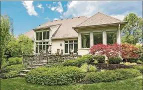  ??  ?? A patio door opens from the sunroom to a circular, elevated paverbrick patio, which is accented by a short stone wall. Stone steps lead down from the patio to the backyard.