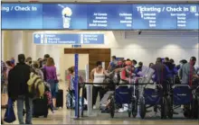  ?? AP PHOTO/JOHN RAOUX ?? Holiday travelers check in at kiosks near an airline counter at Orlando Internatio­nal Airport Tuesday in Orlando, Fla.