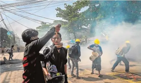  ?? AFP ?? Un manifestan­te vierte Coca-Cola sobre un compañero para aliviar el efecto del gas lacrimógen­o de la Policía