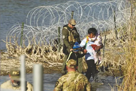  ?? ERIC GAY/ASSOCIATED PRESS ?? MIGRANTS ARE TAKEN INTO CUSTODY BY OFFICIALS at the Texas-mexico border on Jan. 3 in Eagle Pass, Texas. The Supreme Court on Tuesday extended a stay on a new Texas law that would empower police to arrest migrants suspected of illegally crossing the U.s.-mexico border. The order puts the law on hold until at least Monday while the high court considers a challenge by the Justice Department, which has called the law an unconstitu­tional overreach.