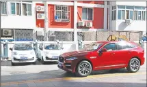  ??  ?? In this file photo, a SUV vehicle drives past electric cars parked at a charging station outside a residentia­l building in Beijing. Automakers face a dilemma in China, where regulators are pressing them to sell electric cars but consumers want...