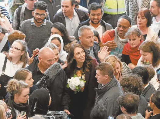  ?? AP Photo / Mark Baker ?? New Zealand Prime Minister Jacinda Ardern is surrounded by supporters at a shopping mall in central Christchur­ch on Wednesday.