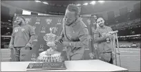  ?? Gerald Herbert / AP ?? Clemson defensive tackle Jabril Robinson (center) takes an up close look at the trophy during media day for the upcoming Sugar Bowl.