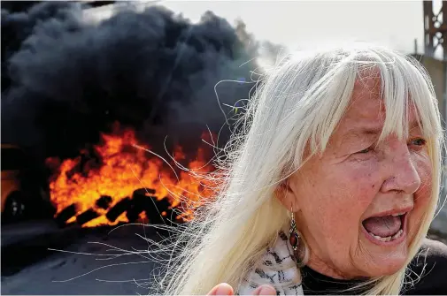 ?? Gideon Saar Justice minister
AFP ?? Israel risks electing a coalition of extremists.
A foreign activist reacts as tires burn behind her during a demonstrat­ion at the Hawara checkpoint, south of Nablus, in the occupied West Bank, on Tuesday. The protesters demanded the reopening of roads around the city, which has been under an Israeli military lockdown since Oct. 11.