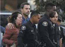  ?? Luis Sinco /Los Angeles Times ?? A woman is escorted away from the area around a law office in Long Beach, where an employee shot two co-workers.