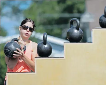  ?? MICHAEL BELL ?? Chelsea Wytrykusz heaves a kettle bell onto a platform Saturday during the Femsport strength and fitness challenge at Gold’s Gym East in Regina. Many competitor­s were inspired by the Olympics.