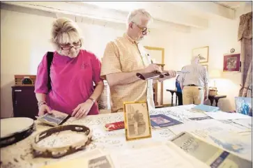  ?? Brandon Dill/special to The Commercial Appeal ?? Nancy Miller (left) peruses a collection of old sheet music while her husband, O.C. Miller, examines an antique rifle. The estate sale at Mount Airy continues today from 11 a.m. to 4 p.m. and Monday from 10 a.m. to 3 p.m.