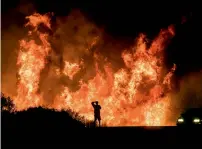  ?? AP ?? UP IN SMOKE: A man watches flames from the Thomas fire leap above the roadway north of Ventura, California on Dec. 6. —