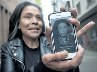  ?? DARRYL DYCK/THE CANADIAN PRESS ?? Maggy Gisle shows her police mugshot from 1994 on her phone, while standing for a photograph in the Downtown Eastside of Vancouver, B.C., last week. For 16 years.