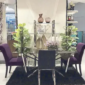  ??  ?? Opulently yours: This dining table sits opulently at the center where a glass-topped table is surrounded by contempora­ry dining chairs in plush purple velvet upholstery mixed with a leather dining chair for accent.