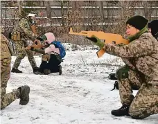  ?? Foto: Profimedia ?? Ukrajinští dobrovolní­ci a dobrovolni­ce cvičí nedaleko hlavního města Kyjeva s dřevěnými maketami samopalů .