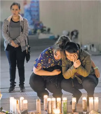  ?? NICK OZA FOR USA TODAY ?? Sara Rivero, right, and her mom, Laura Rodriguez, burn a candle at a memorial site in Las Vegas.