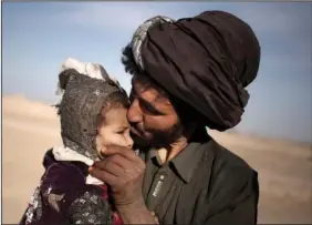  ?? ?? A nomad kisses his young daughter Oct. 20, 2012, while watching his herd in Marjah, Helmand province, Afghanista­n.