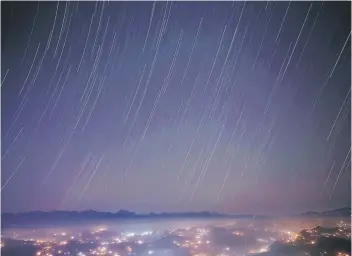  ??  ?? A long exposure picture shows a star trail above the mountain range during the Geminids meteor shower celestial event in Nagarkot, Nepal. — Reuters photo