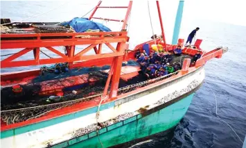  ??  ?? The foreign fishermen seen huddled in their vessel after they were intercepte­d by the Navy ship on Sunday.