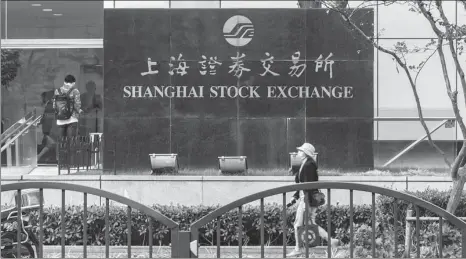  ?? WANG GANG / FOR CHINA DAILY ZHANG HENGWEI / CHINA NEWS SERVICE ?? Above: A pedestrian passes the Shanghai Stock Exchange in Pudong New Area.
Left: A visitor poses in front of the bull statue at the Bund in Shanghai on Feb 14. The city has recently moved up the global financial center rankings.