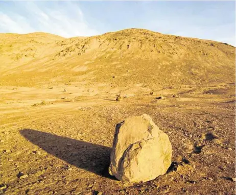  ??  ?? A boulder sits in Chile’s Chuculay Boulder Field; the escarpment it fell from is in the background. Craters in a Chilean desert preserve the trajectori­es of giant rocks, allowing scientists to study the physics of rockslides.