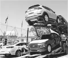  ??  ?? Automobile­s are on a truck for delivery to a car lot in Queens, New York. Filling the fuel tank for vacation driving this summer will be pricier than it has been in nearly four years for American motorists, as gasoline prices nationwide rise toward the...