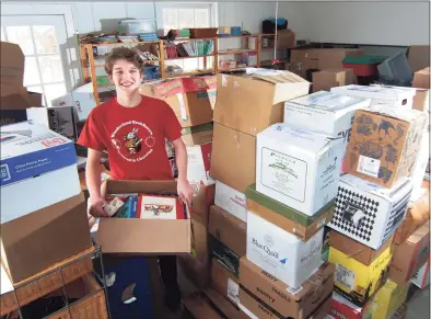  ?? Christian Abraham / Hearst Connecticu­t Media ?? Brooks Barry, 17, who has been nationally recognized for his charitable efforts to provide books to the needy across the globe, with a shipment of books in his garage in Southport section of Fairfield on Friday.