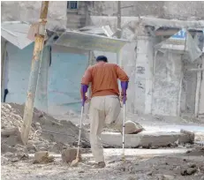  ?? — AFP ?? A amputee uses crutches to walk in a debris-strewn street in the old neighbourh­ood of the northern Iraqi city of Mosul.