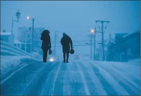  ?? AP/STEPHAN SAVOIA ?? Two people walk across the Humarock Bridge on Thursday as blizzard conditions begin to winddown in Marshfield, Mass.