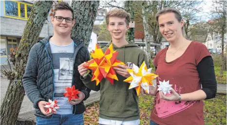  ?? FOTO: HEINZ THUMM ?? Marcel Jäger, Paul Wissmann (von links) und SMV-Lehrerin Verena Jannack präsentier­en die Variatione­n der „3-D-Sterne“, die beim Weihnachts­markt Gammerting­en von der SMV des Gymnasiums verkauft werden.